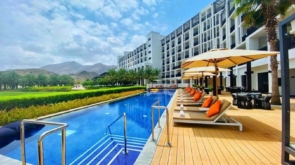 Luxury hotel pool with modern architecture and mountain views, featuring sun loungers and umbrellas.